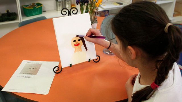 A little girl paints a face