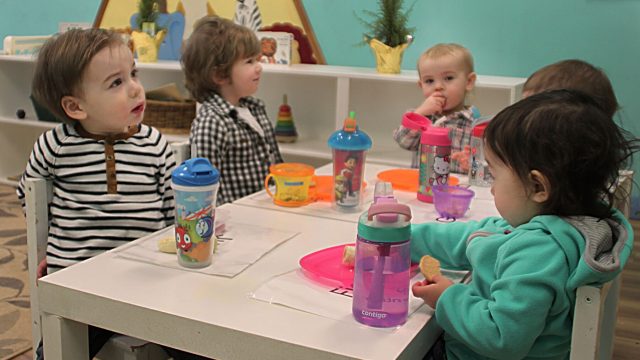 A group of toddlers sitting at a table eating snacks