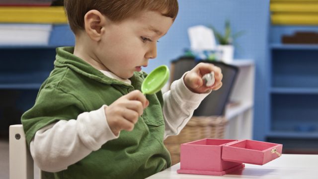 Toddler holding items to put in a pink box