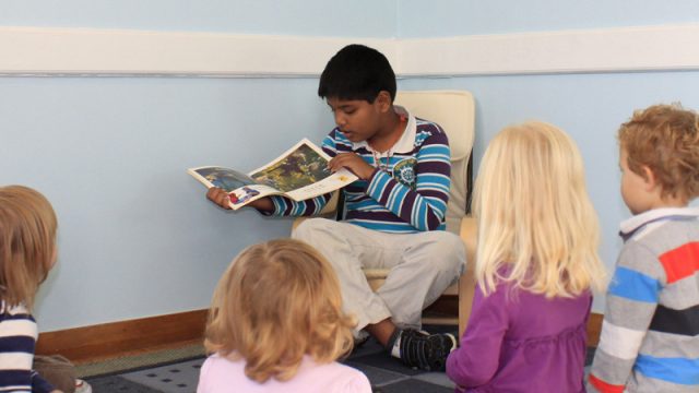 Little boy reads to his classmates and shows pictures